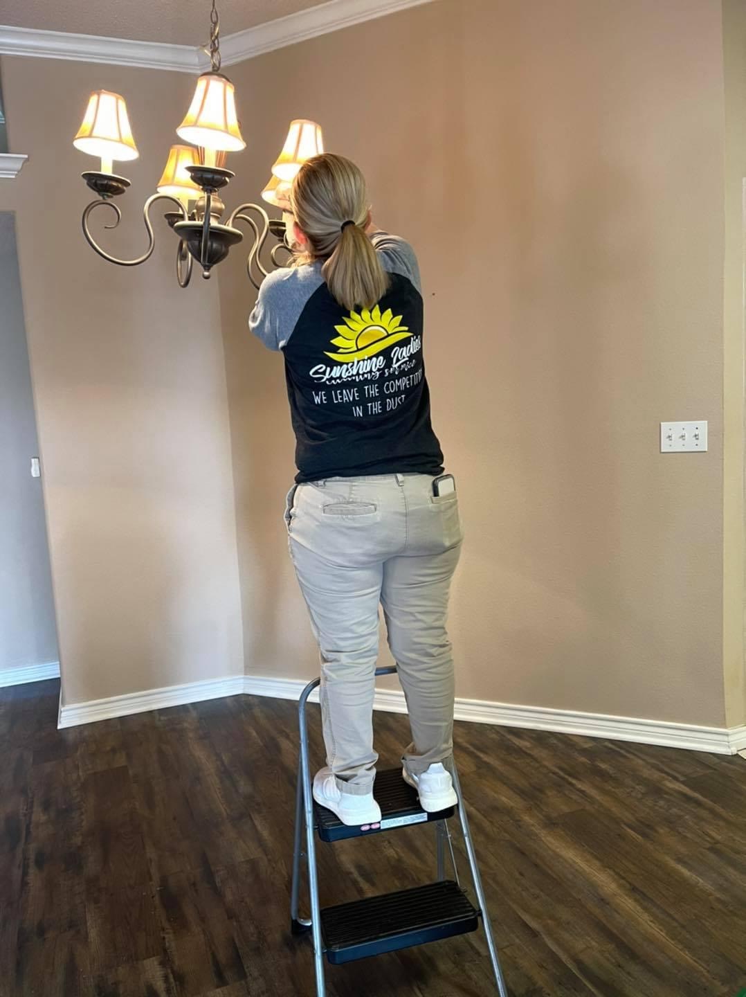 Sunshine Ladies team member cleaning a chandelier
