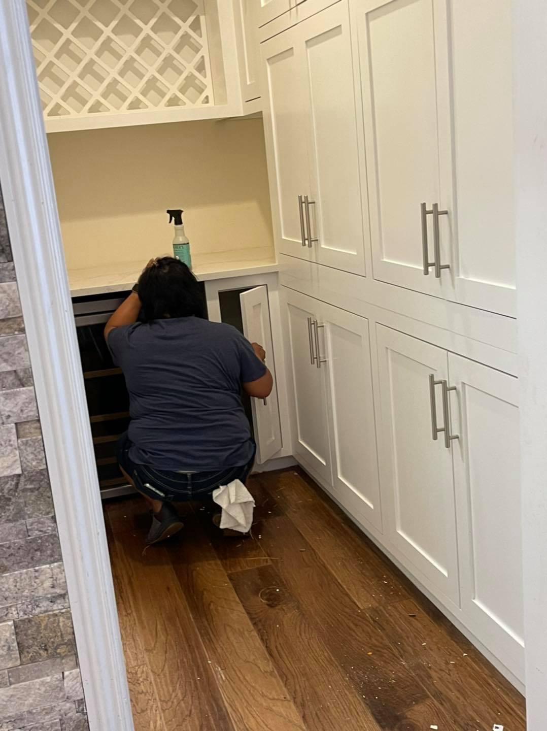 Cleaning cabinets in a white kitchen